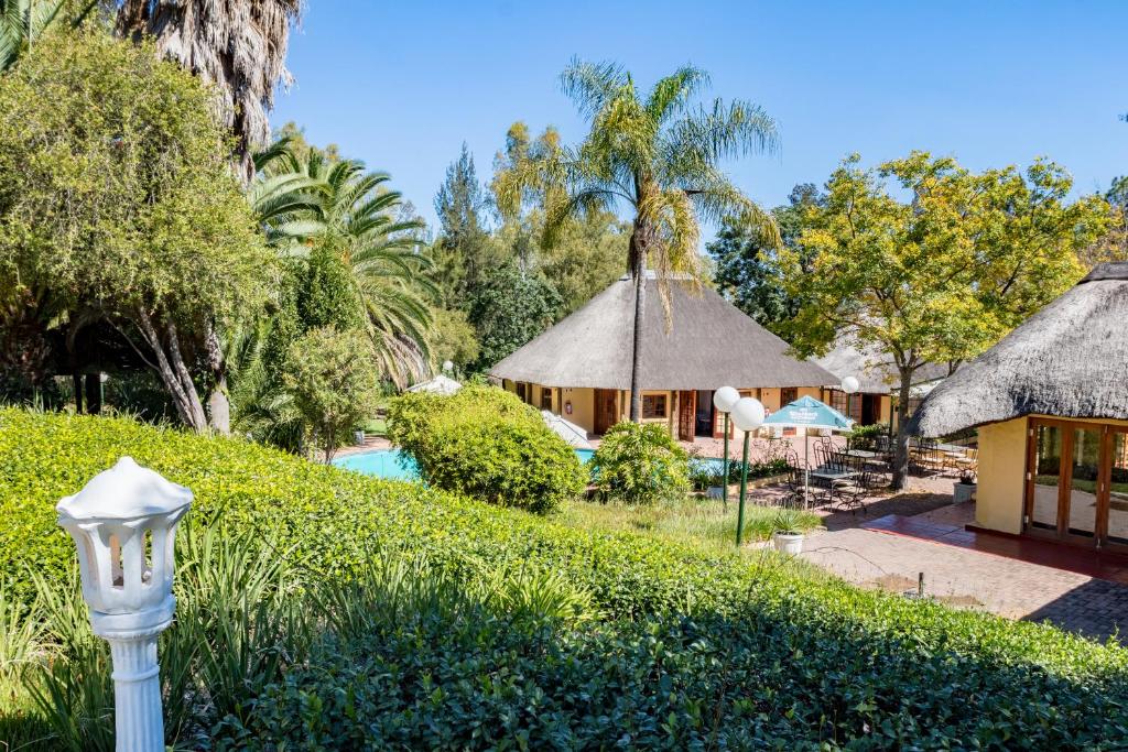 - une vue sur un complexe avec une piscine et des arbres dans l'établissement Shumba Valley Lodge, à Lanseria