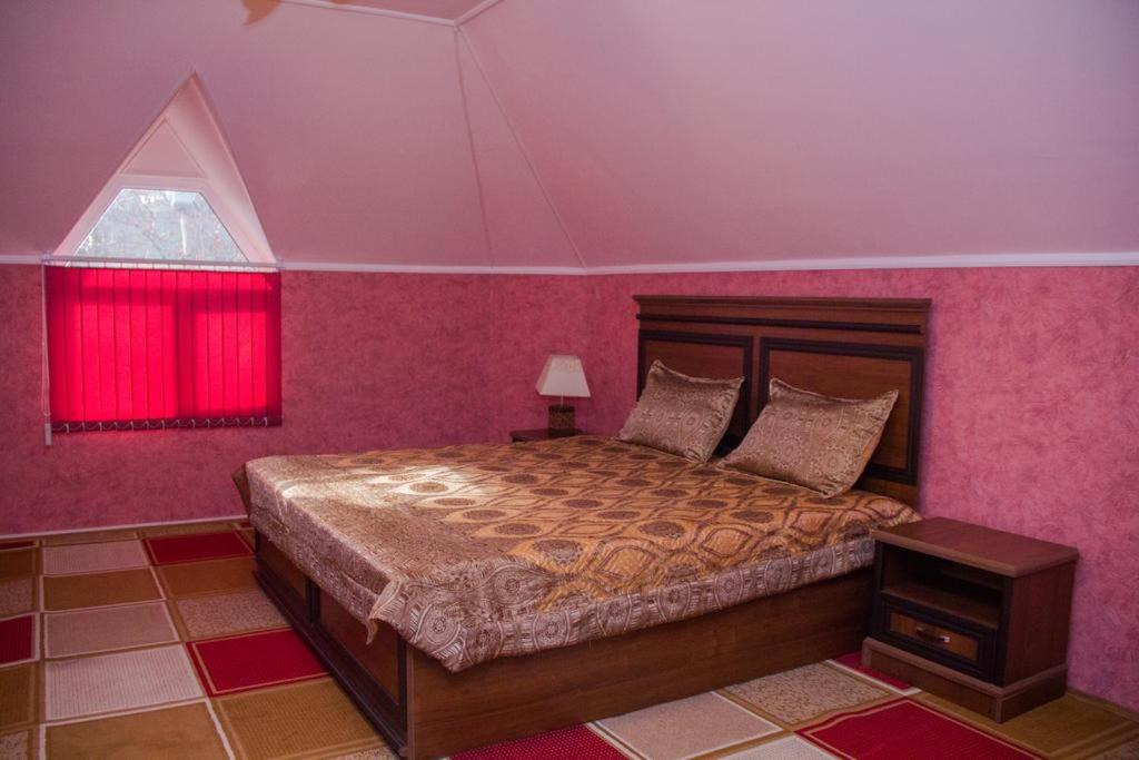 Schlafzimmer mit einem Bett mit rosa Wänden und einem Fenster in der Unterkunft Hotel Matin on Moskovskay in Chkalovsk