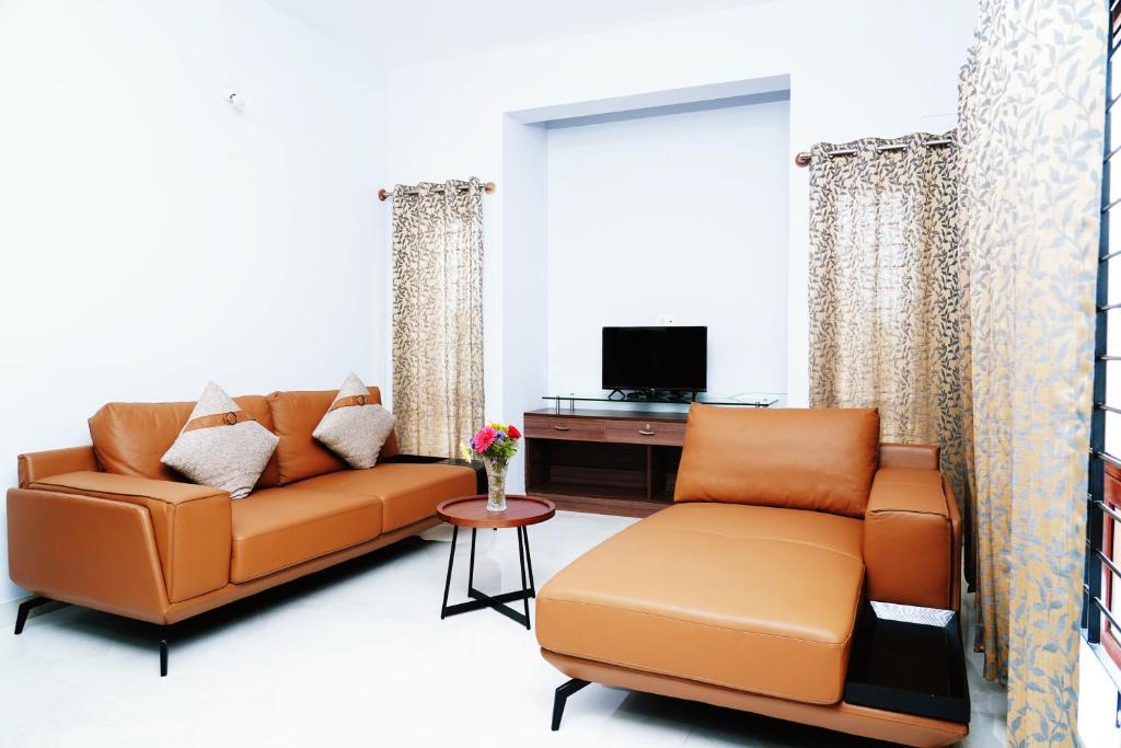 sala de estar con sofá y TV en UNNATHI SUITES, en Mysore