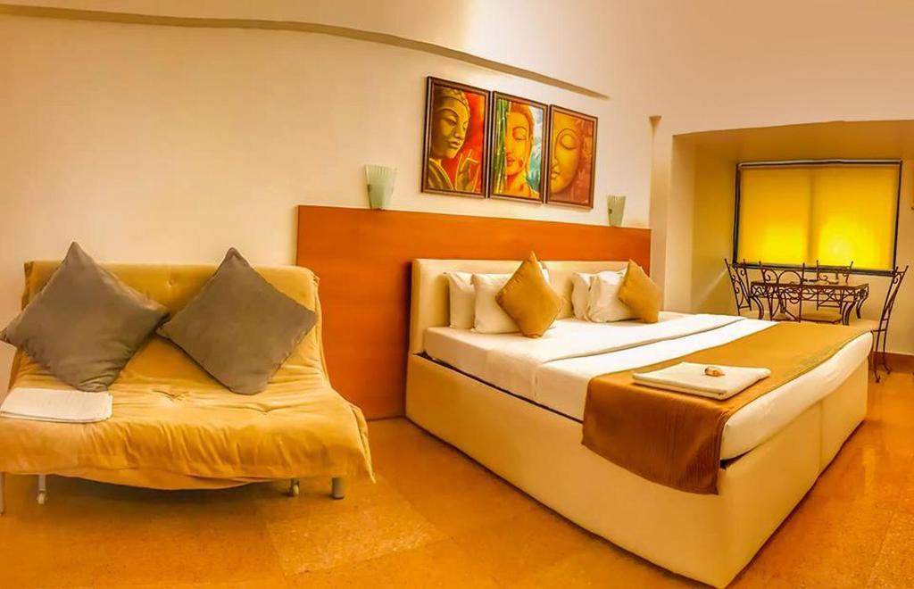 a hotel room with a bed and a couch at Hotel Samraj in Mumbai