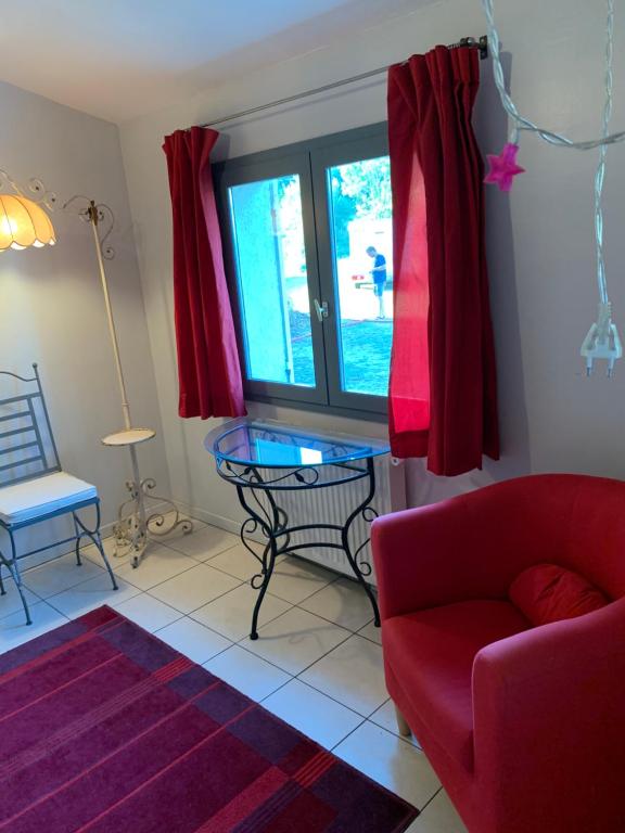 - un salon avec un canapé rouge et une table en verre dans l'établissement La Meyssonnié, à Damiatte