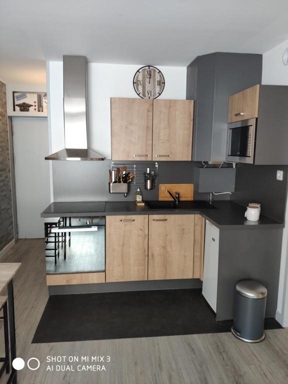een keuken met zwarte aanrechtbladen en houten kasten bij Appartement Résidence Armazan - pieds de piste in Saint-Lary-Soulan