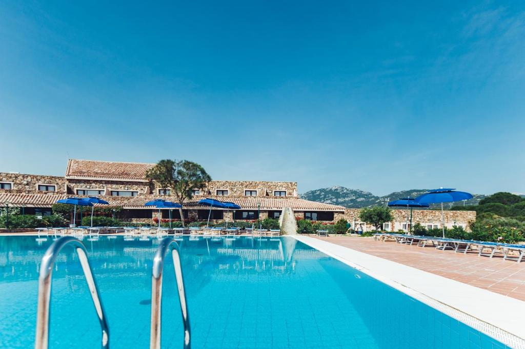 a swimming pool with blue water and umbrellas at Residence Hotel Nuraghe in Porto Rotondo