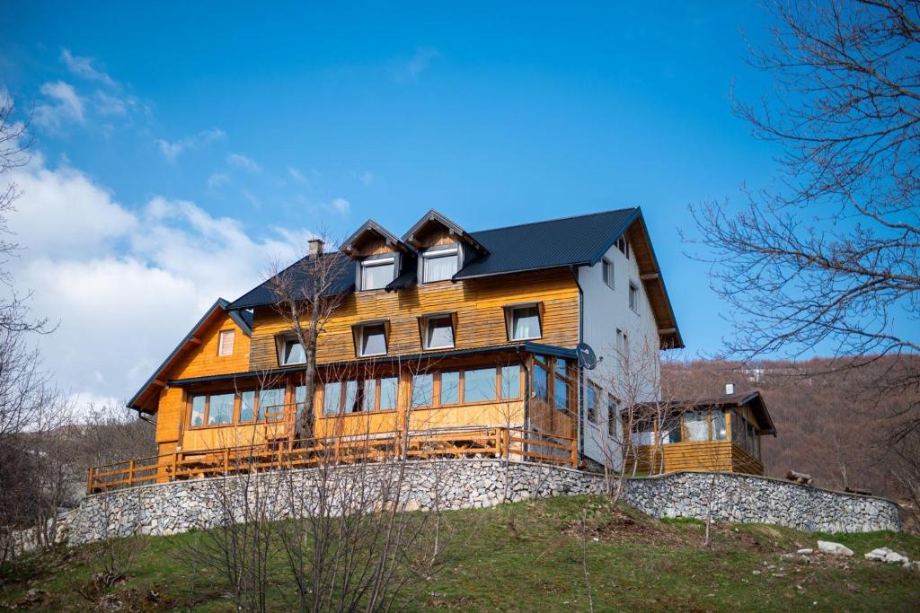 duży drewniany dom na szczycie wzgórza w obiekcie Bed and Breakfast Umoljani w mieście Umoljani