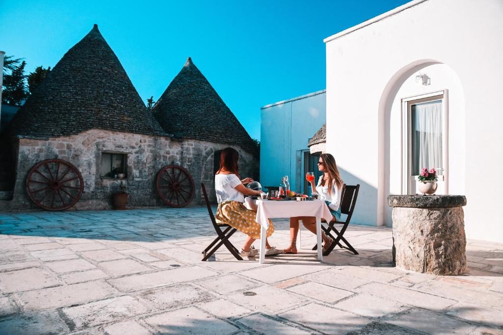 two women sitting at a table in front of a building at Casale Dei Pini - Nature Room in Martina Franca