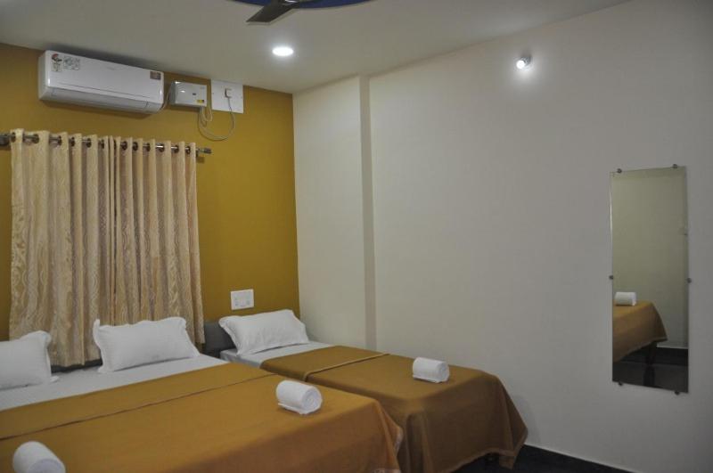 um quarto com 2 camas num quarto com uma ventoinha em Blue Crystal Lodge em Shimoga