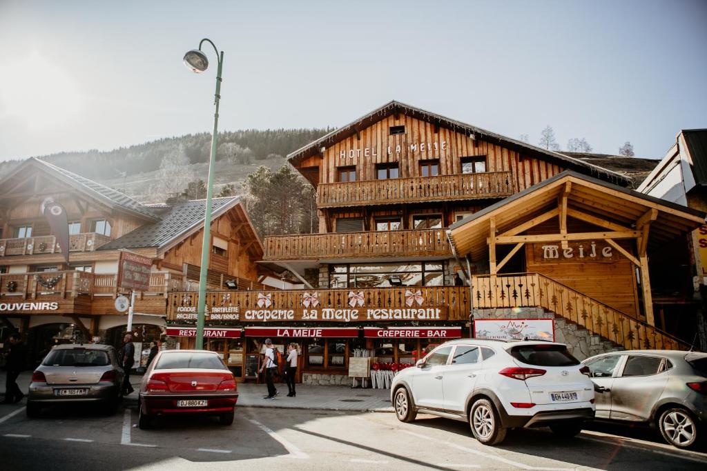 un gran edificio de madera con coches aparcados delante de él en Hotel La Meije, en Les Deux Alpes