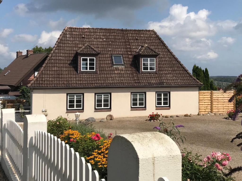 a white house with a brown roof and a fence at Ferienhaus Vogelberg in Lütjenburg