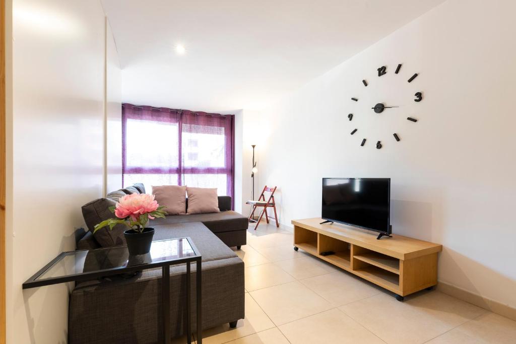 a living room with a couch and a clock on the wall at Stay Barcelona Sant Martí in Barcelona