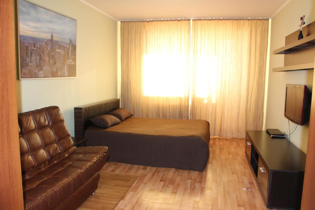 1 dormitorio con cama, sofá y TV en Apartments on Buinskiy 1, en Ulyanovsk