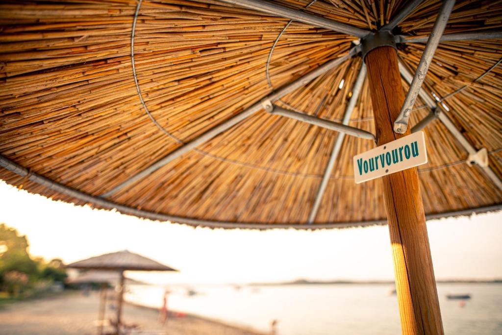 a wooden umbrella with a sign on a pole at Kokkinos in Vourvourou
