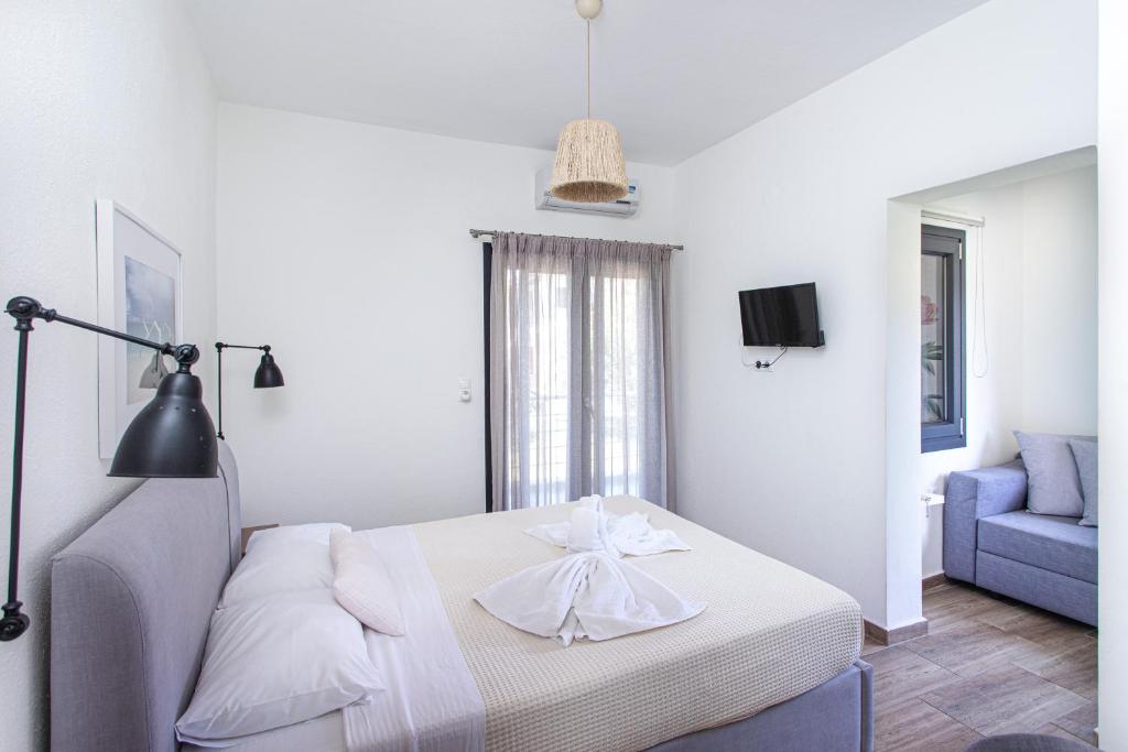a white bedroom with a bed and a blue couch at Kokkinos in Vourvourou