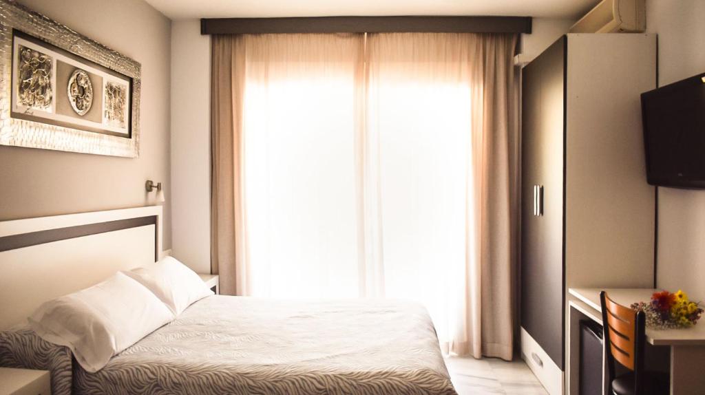 1 dormitorio con cama y ventana grande en Hotel Albero, en Granada