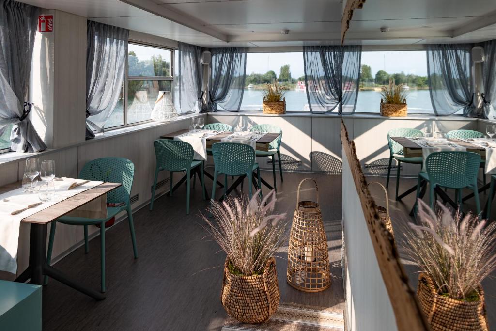 restauracja ze stołami, krzesłami i oknami w obiekcie Marina Azzurra Resort w Lignano Sabbiadoro