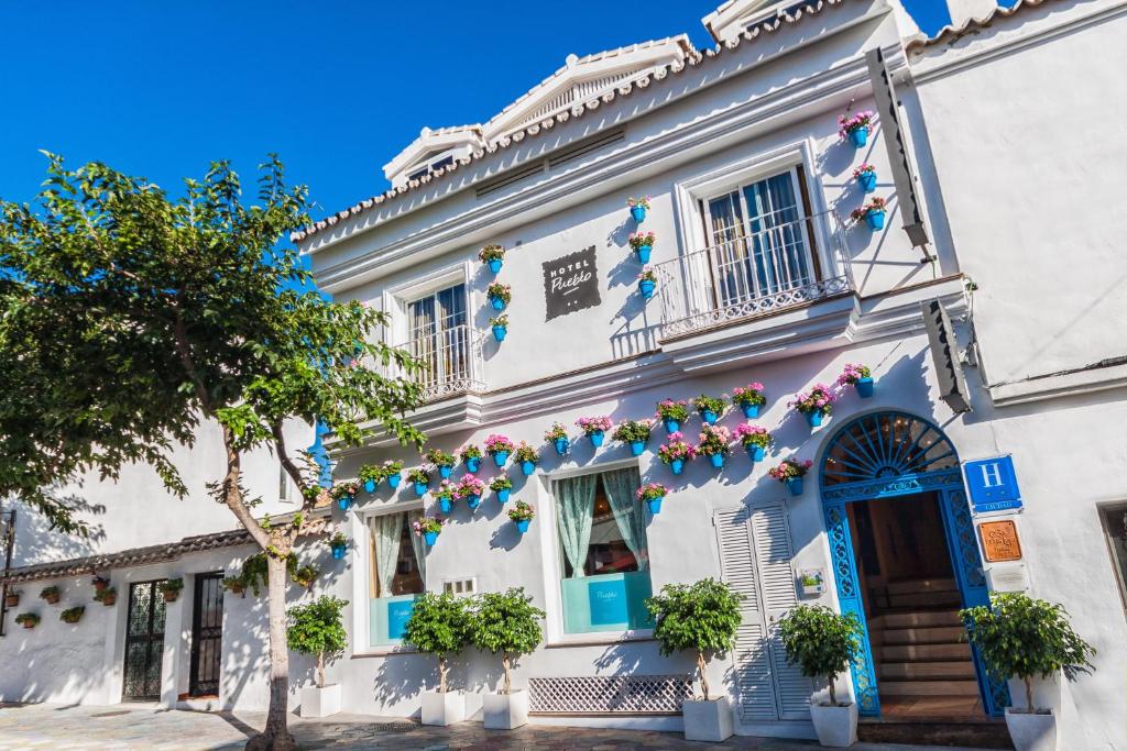 a white building with blue doors and flowers on it at Boutique Hotel Pueblo in Benalmádena