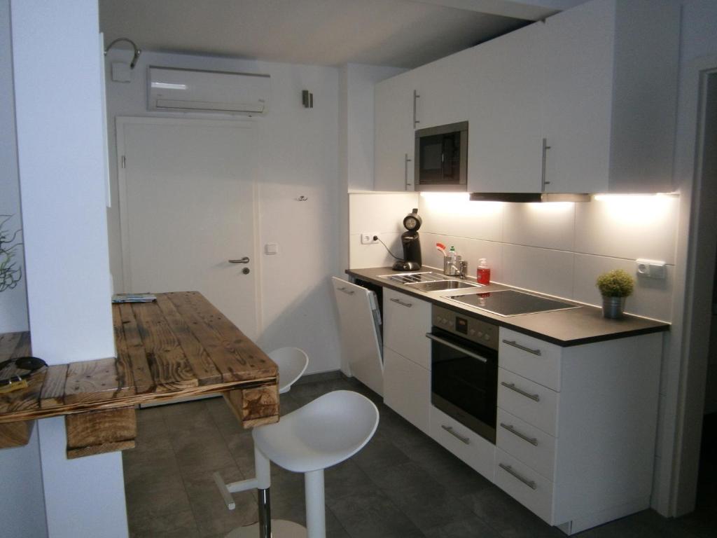 une cuisine avec des placards blancs et une table en bois dans l'établissement Alles Paletti mit Klimaanlage, à Wittemberg