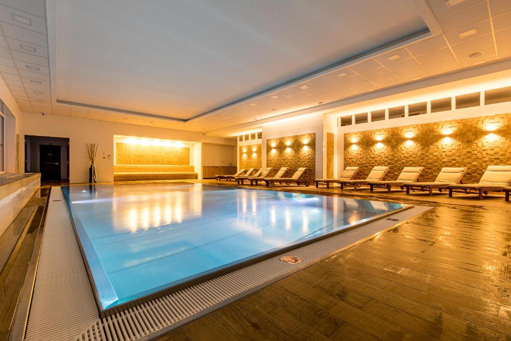 a swimming pool in a large room with chairs at Rezidence Moser Apartments in Karlovy Vary