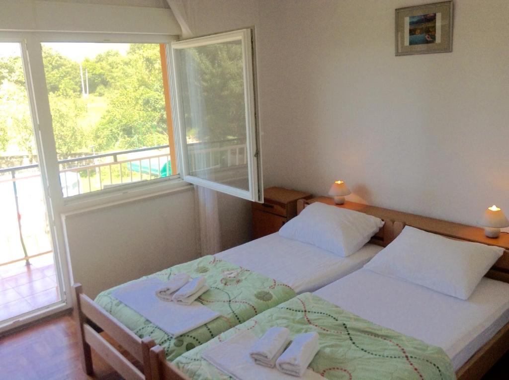 dwa łóżka pojedyncze w pokoju z oknem w obiekcie Apartman Katica w mieście Plomin