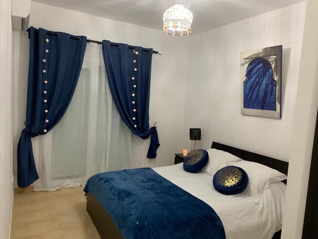 a bedroom with a bed with blue pillows on it at Oriental Dary Al Waha Marina Saidia in Saidia 