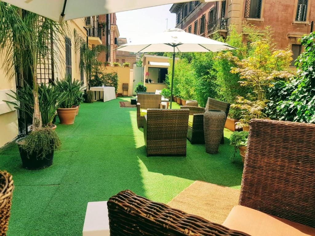 a patio with grass and chairs and an umbrella at Hotel Coppede' in Rome