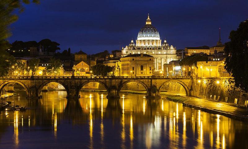 a bridge over a river with a building at night at Hotel Coppede' in Rome