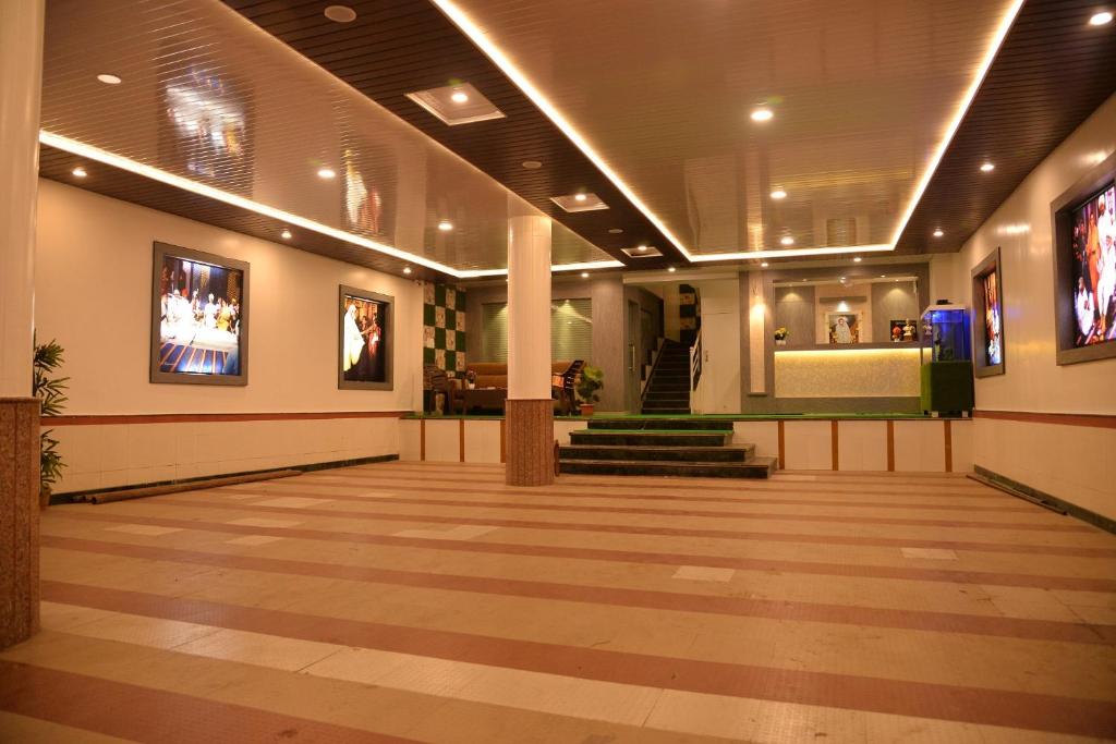 un pasillo con un vestíbulo con escaleras y pinturas en Hotel Disha Palace, en Shirdi