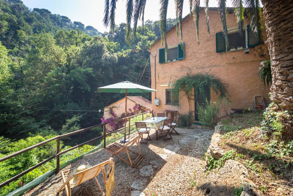a house with a table and an umbrella on a balcony at Casa Cassandra. Relax & Privacy ad un passo da Portofino in Paraggi