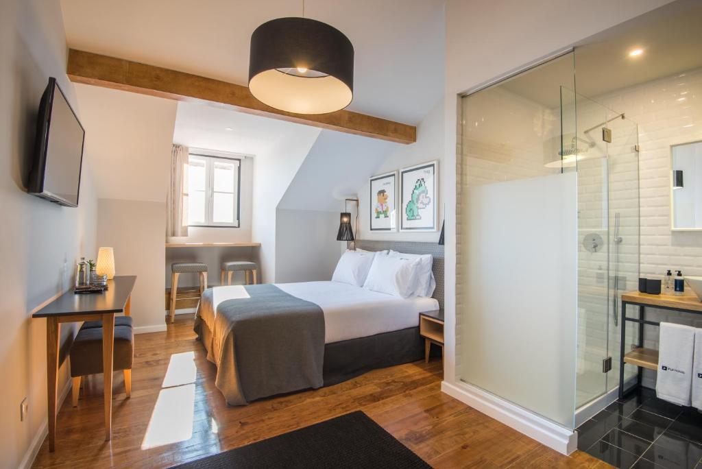 a hotel room with a bed, desk and a television at Urbano FLH Hotels Lisboa in Lisbon