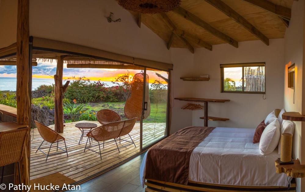 1 dormitorio con 1 cama y patio con sillas en Kona Koa Lodge, en Hanga Roa