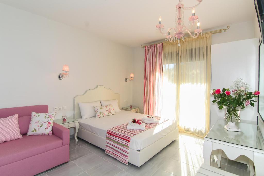 a living room with a bed and a pink couch at Golden Blue Studios in Chrysi Ammoudia