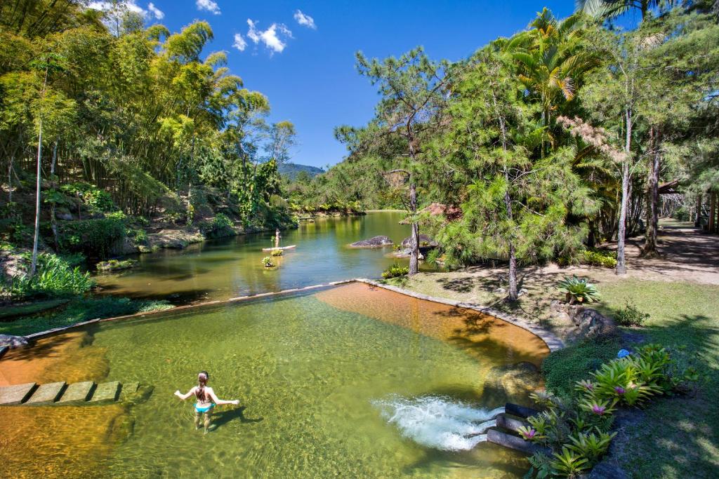 uma mulher parada numa piscina de água num rio em Eco Resort Hotel Villa São Romão em Lumiar