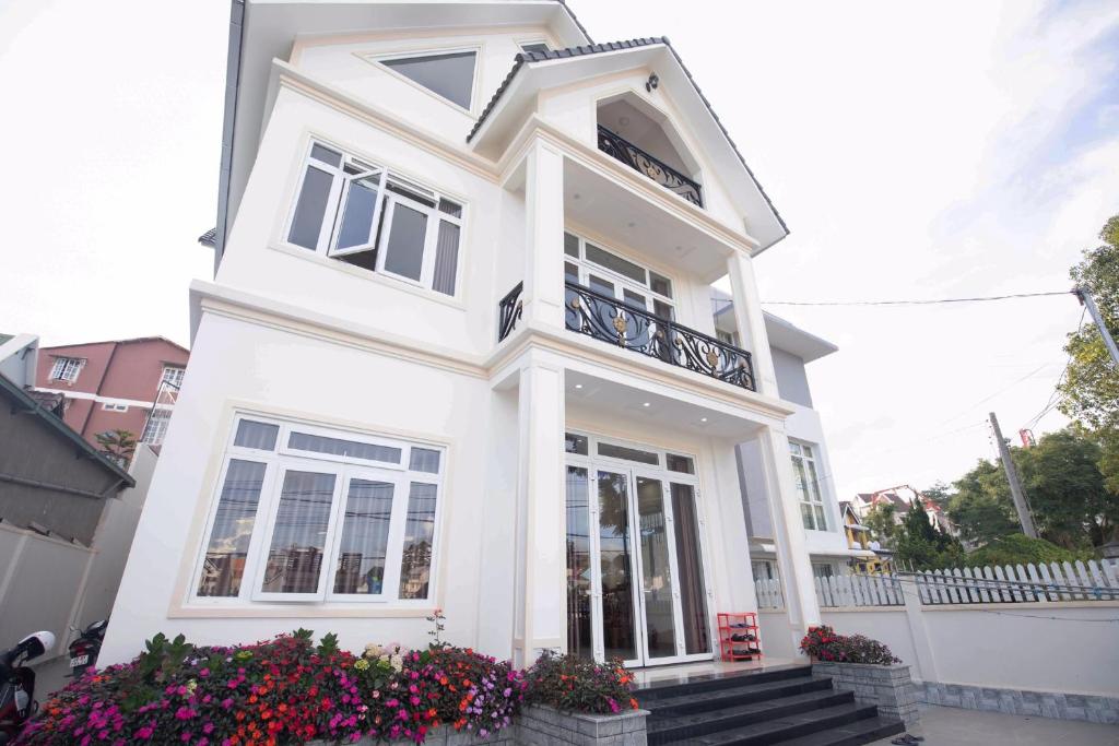 a white house with a balcony and flowers at HUNA House in Da Lat