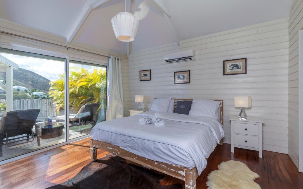 une chambre avec un lit et une grande fenêtre dans l'établissement Villa La Voile Blanche, à La Baie-Orientale