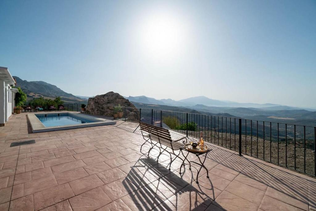 un patio con un banco y vistas a las montañas en Villa with views and private pool near Malaga., en Colmenar