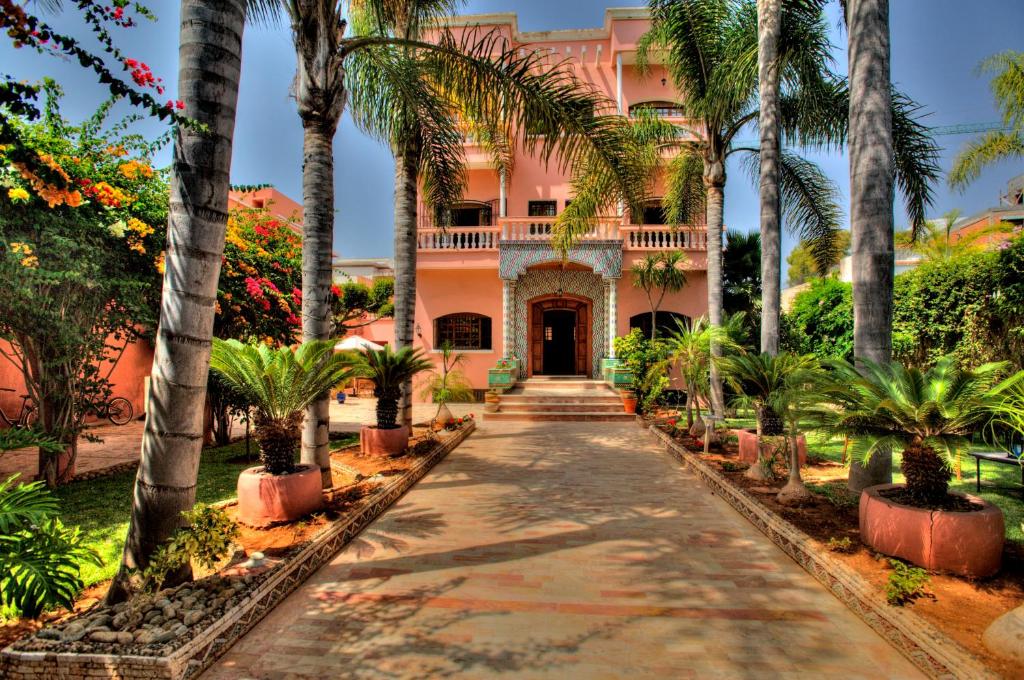 a pink house with palm trees and a walkway at LHOSTEL à Casablanca in Casablanca