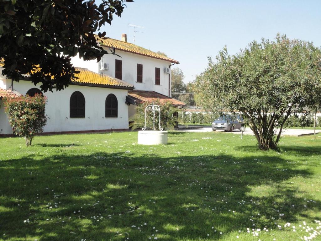 un patio verde con una casa blanca y árboles en B&b Tenuta di Vado Piano nella Selva di Circe, en Pontinia