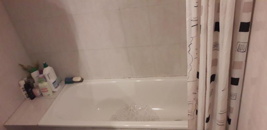 El baño incluye bañera blanca con cortina de ducha. en Rio de Mouro Quartos, en Sintra