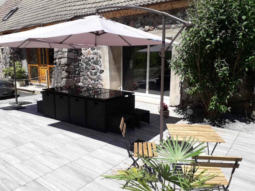 a patio with an umbrella and a table and chairs at Mas du Cresponnet in Murat