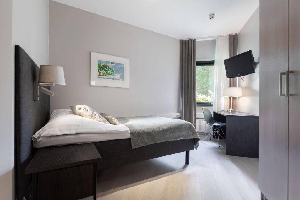 una camera con letto, scrivania e TV di Majvik Congress Hotel a Kirkkonummi