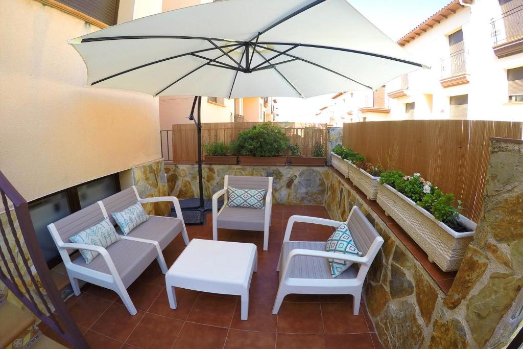 a patio with chairs and a table and an umbrella at Casa en el valle del tietar in Lanzahita