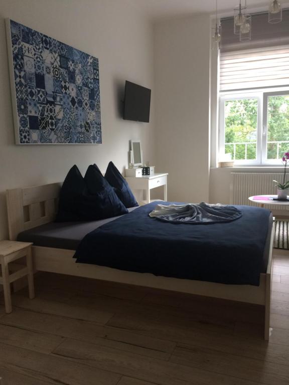 sypialnia z łóżkiem z niebieskimi prześcieradłami i oknem w obiekcie Apartmán nad Imperiálem w Karlowych Warach