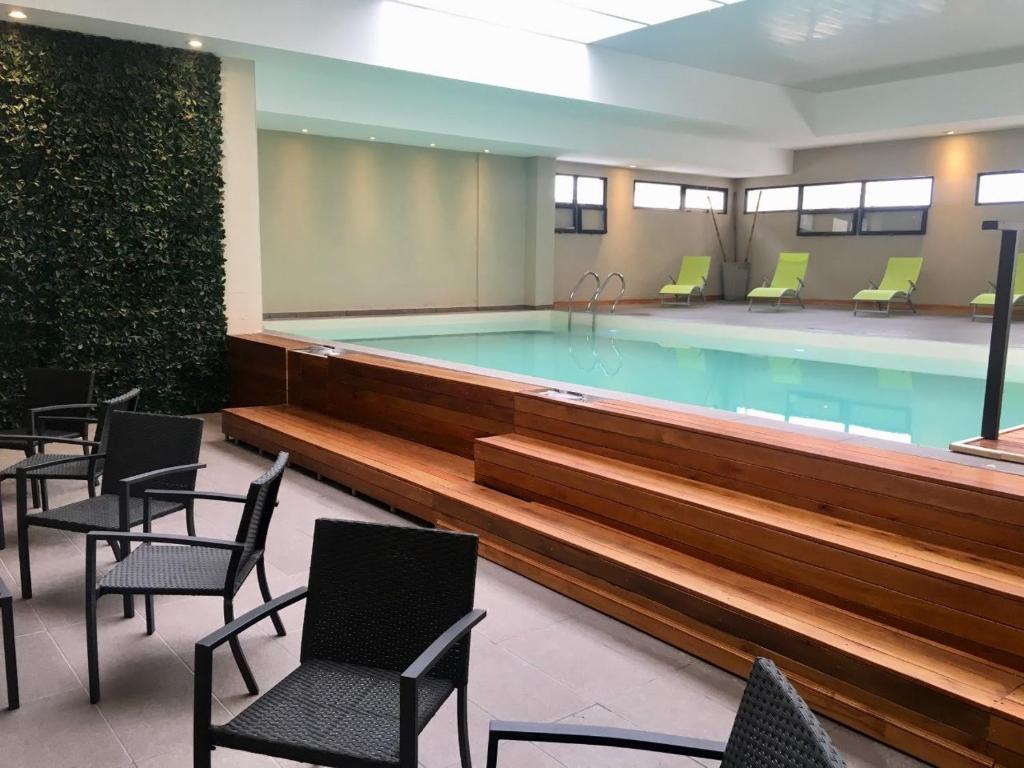 a large swimming pool in a building with chairs at Michelle- Departamentos in Necochea