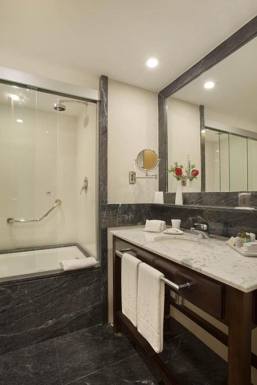 a bathroom with a tub and a sink and a mirror at Windsor Marapendi Hotel in Rio de Janeiro