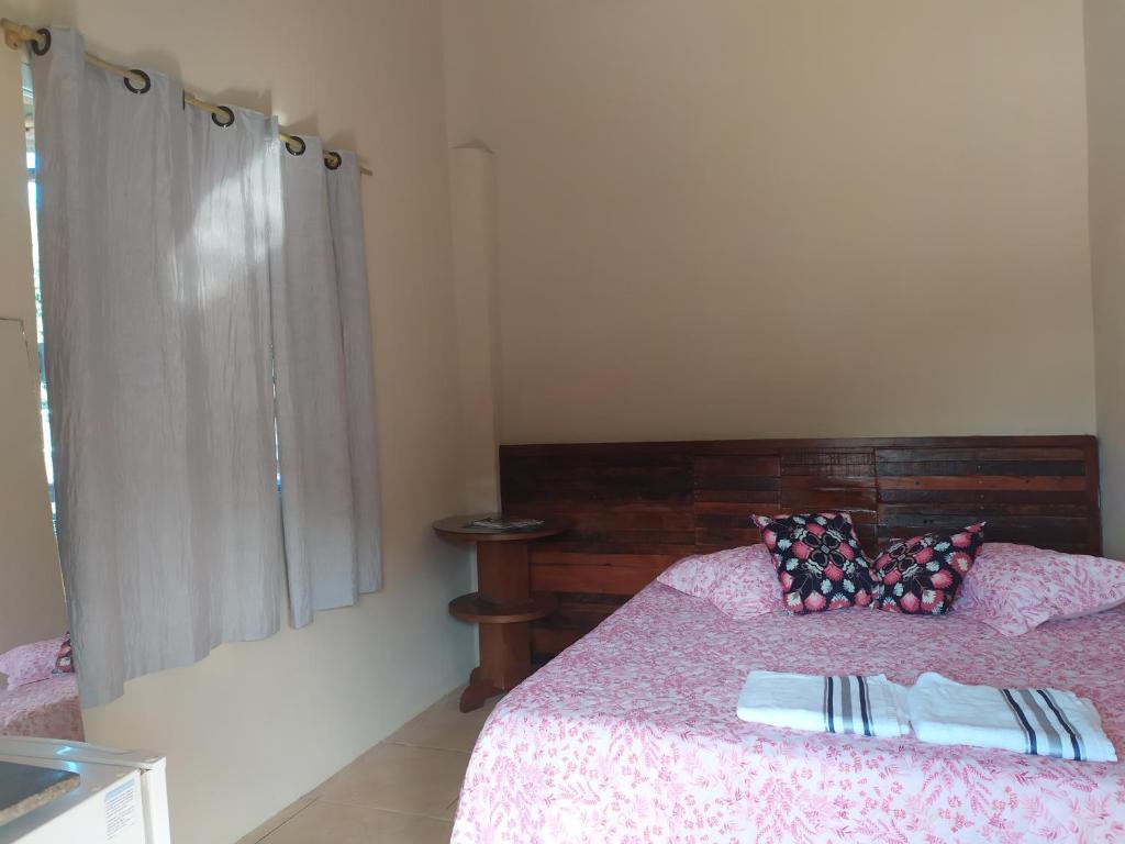 a bedroom with a bed with a wooden head board at Suítes Praia das Toninhas in Ubatuba