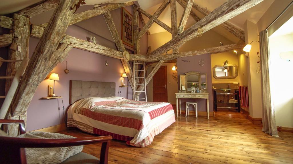 een slaapkamer met een bed in een kamer met houten balken bij La part des anges in Pupillin