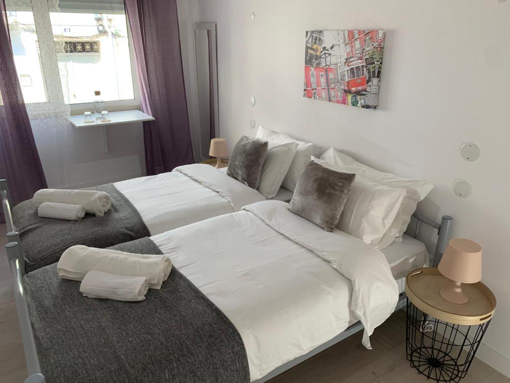 a bedroom with a large bed with white sheets and pillows at Santo Amaro Apartment in Lisbon