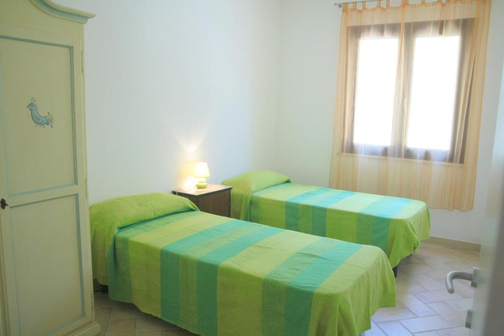1 dormitorio con 2 camas con sábanas verdes y azules en Casa al mare La Palma, en Santa Maria Navarrese