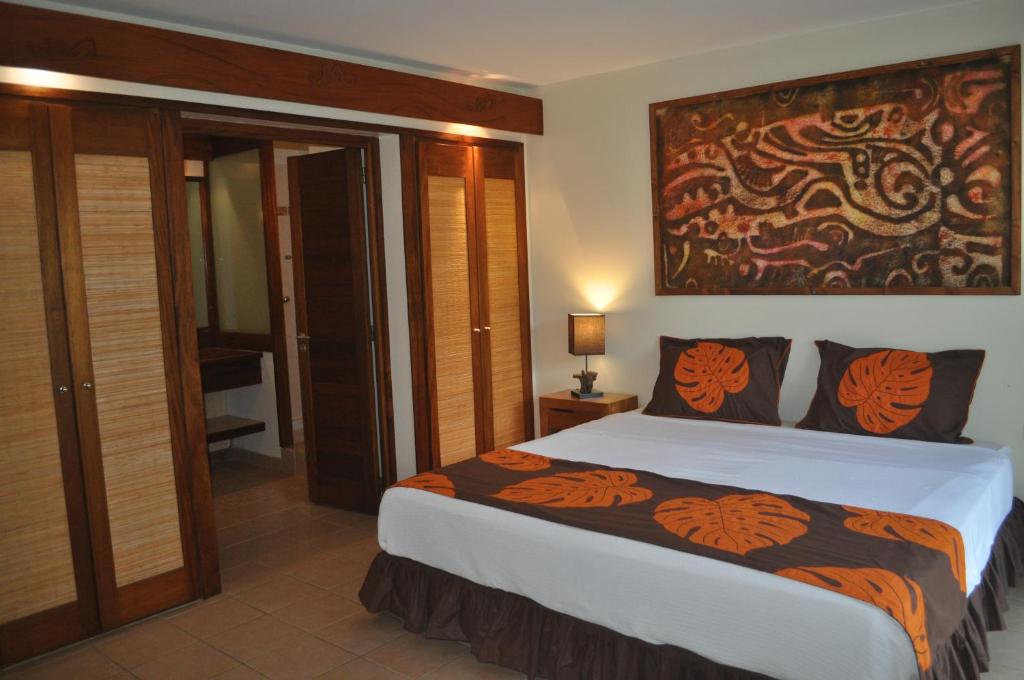 a bedroom with a large bed with orange and black pillows at ROYAL BORA BORA in Bora Bora