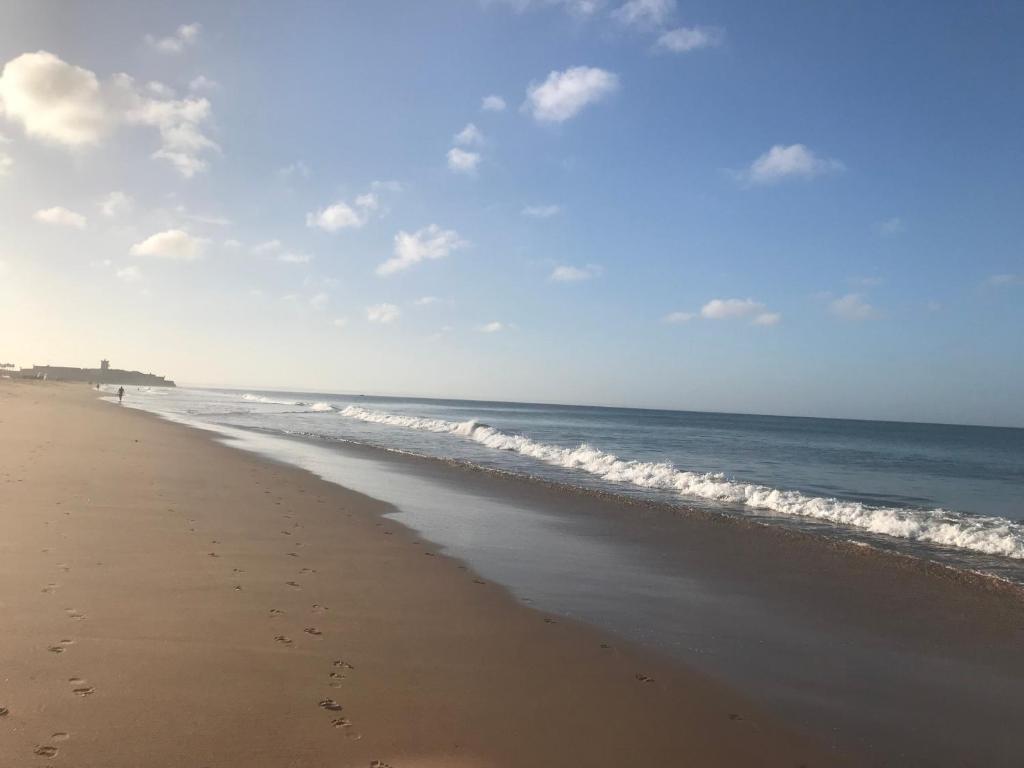 a beach with footprints in the sand and the ocean at Atlantic Waves Accommodation in Carcavelos