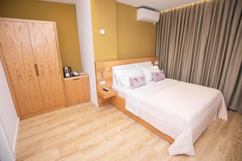 Schlafzimmer mit einem weißen Bett und Holzboden in der Unterkunft Hotel Elior in Tirana